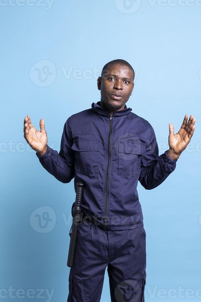 African american security agent acting surprised and in shock in front of the camera, wearing guarding uniform and baton. Officer working on protecting people and securing places. photo