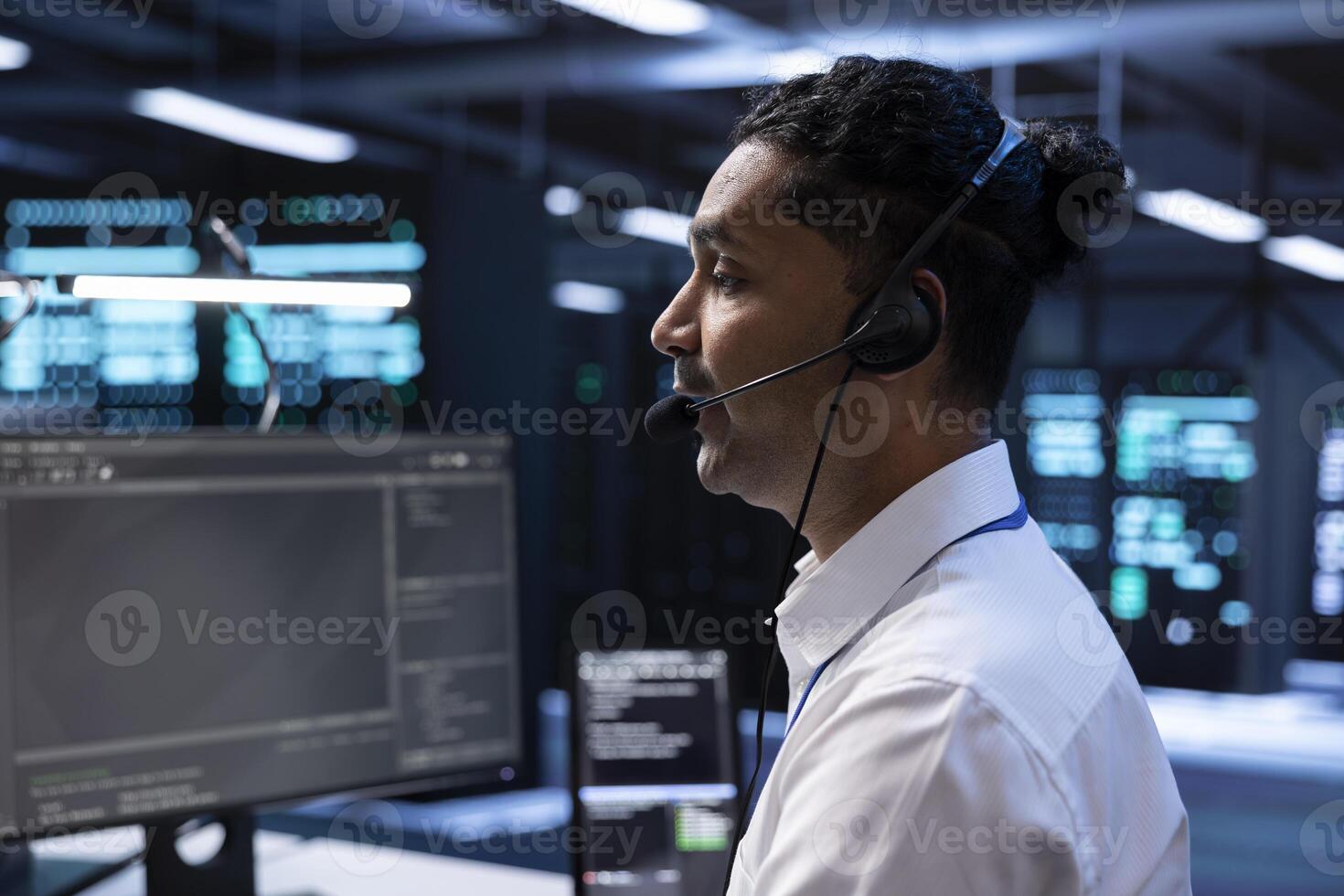 IT staff member in data center supporting engineering team doing equipment maintenance, talking in headset microphone. Worker in server room coordinating technicians using mic photo