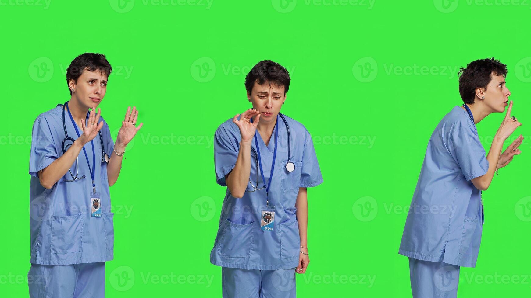 Medical assistant asking to keep quiet and be silent against greenscreen, showing hush mute symbol to keep privacy and silence. Young nurse showing secrecy taboo sign. Camera B. photo