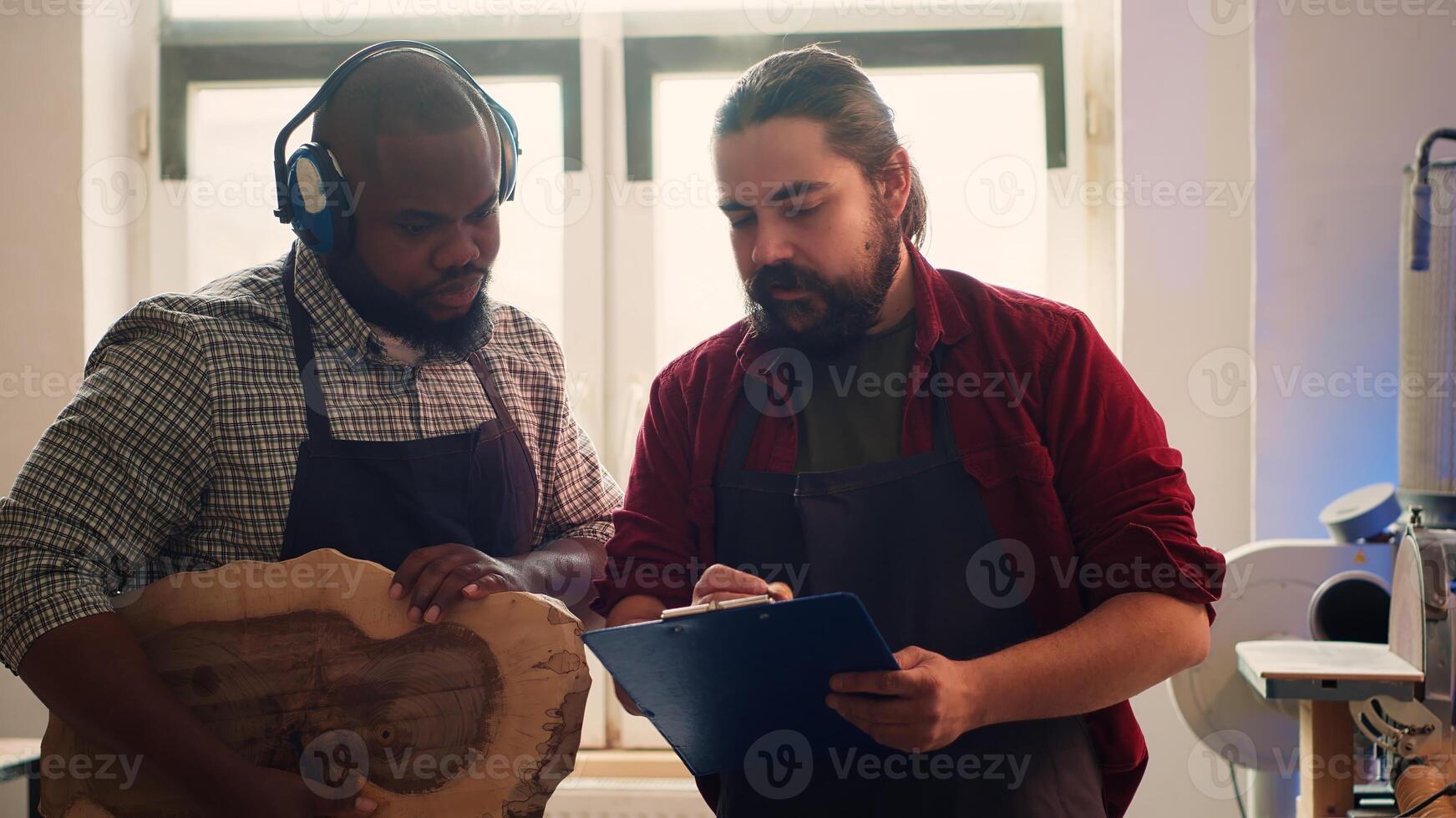 Woodworker looking over blueprints on laptop, brainstorming with colleague next steps in wood processing. Manufacturer and BIPOC apprentice reading furniture assembly schematics in studio, camera A photo