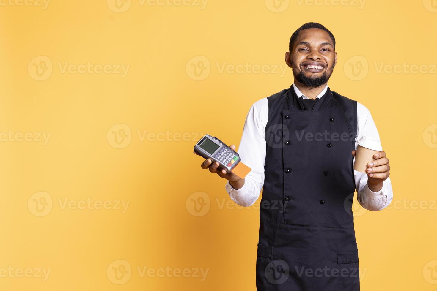 Professional friendly waiter showing the pos terminal with a credit card, symbolizing electronic payments for a meal. Restaurant employee works in a service oriented industry. photo