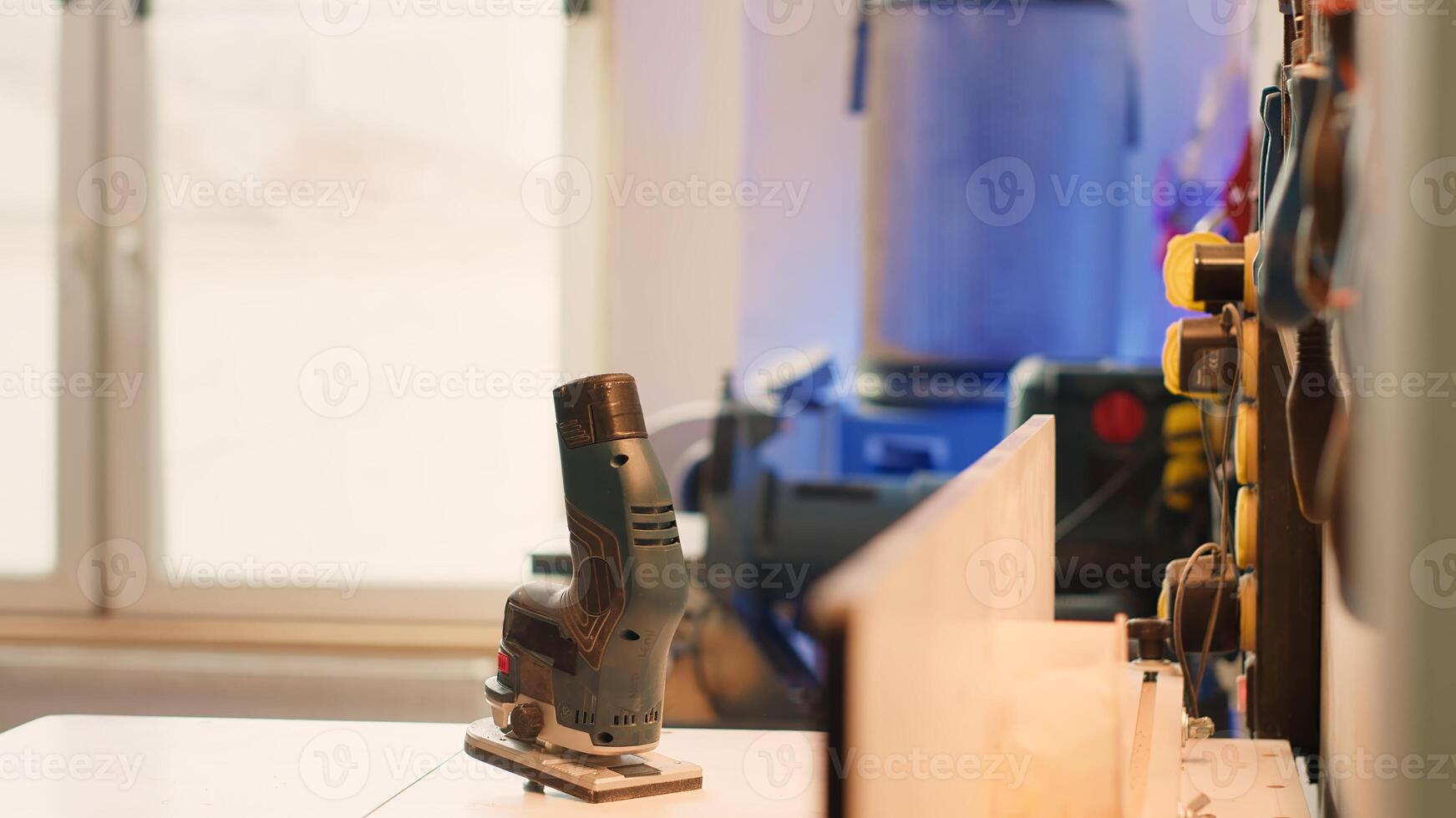 Chisels, screwdrivers, wrench and pliers on wall in furniture assembly shop next to electric router on workbench. Close up of woodworking gear on rack in joinery and power tool photo