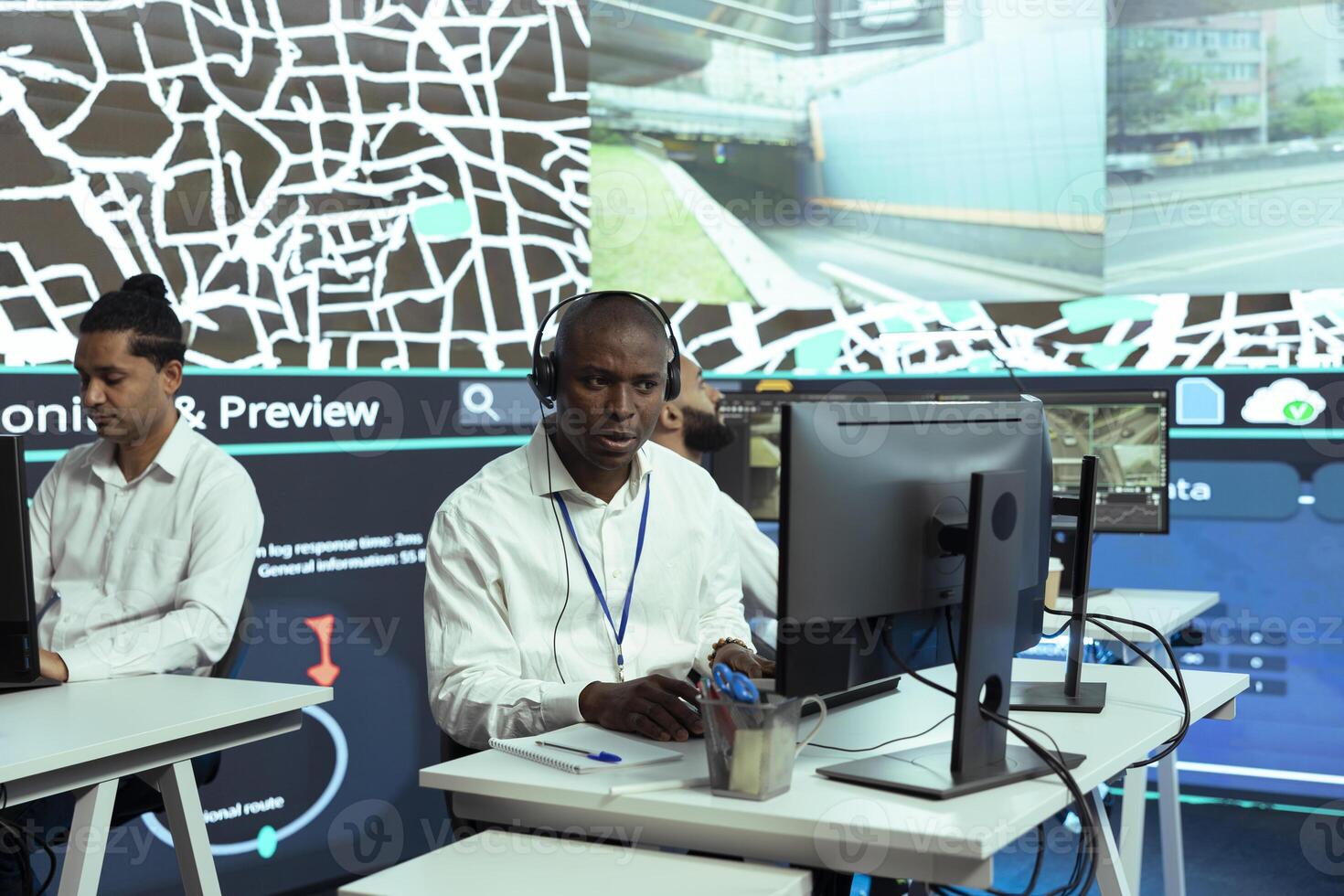 African american man offers updates to clients via order tracking service, monitoring delivery trucks through city traffic and providing gps coordinates. Dispatch employee in control center. photo