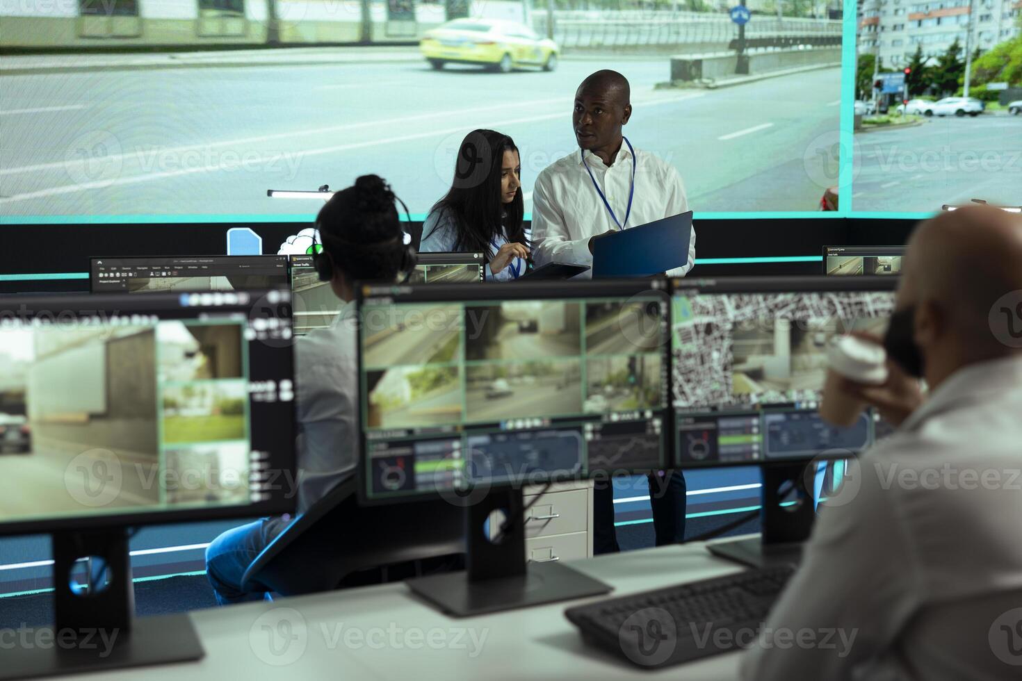 Indian manager working with her staff to gather intelligence by reviewing security camera footage, monitoring traffic through CCTV system. Diverse agency employees oversee surveillance. photo