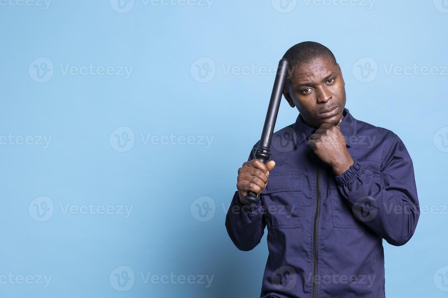 Dangerous skilled bodyguard posing with his baton weapon and clenched fist, making threats in case of fights or emergency defense. Agent on security and protection duty trained to punch. photo