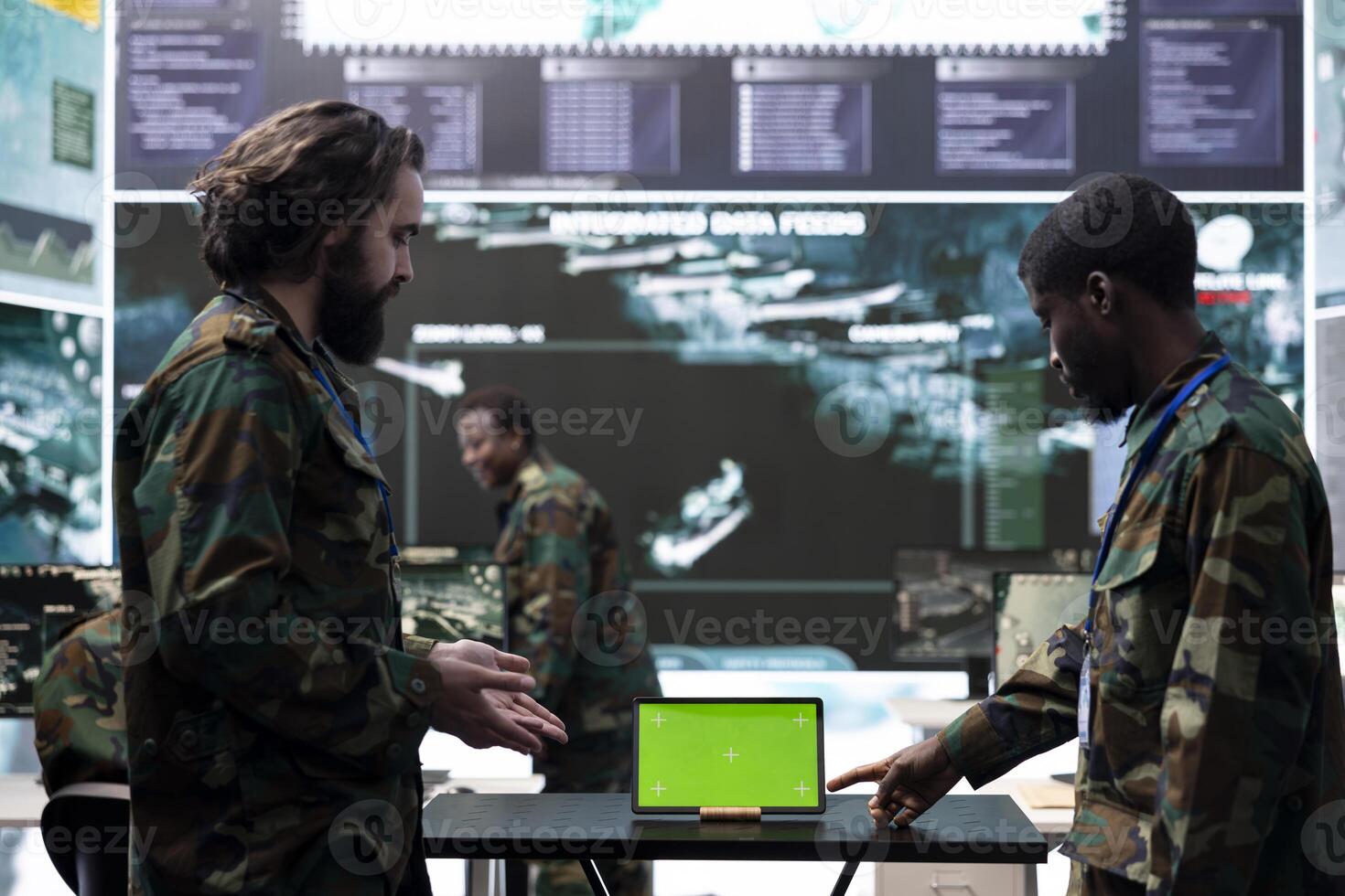Diverse team of soldiers collecting information from a green screen, employing a tablet in military base of operations. Skilled IT engineers examining activity in control center, high tech. photo