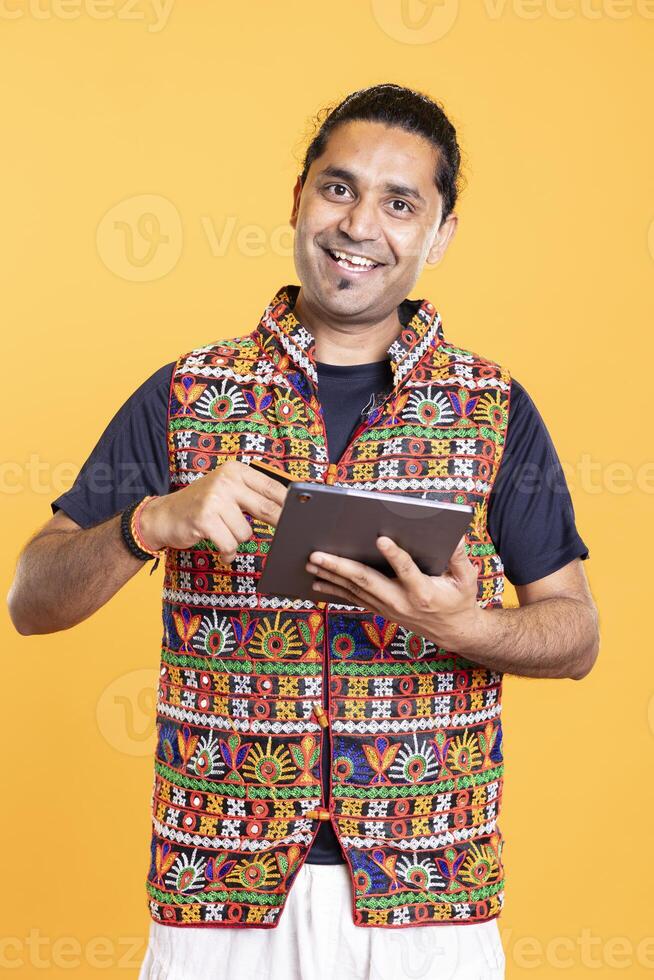 Portrait of happy man smiling while adding payment method on tablet, delighted to take advantage of promotions. Ecstatic person excited to do internet shopping on digital device, studio background photo
