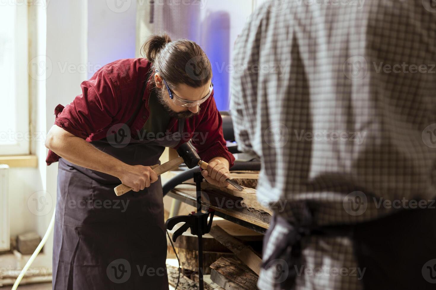 Experienced woodworker shaping raw timber using chisel and hammer in carpentry shop, enjoying diy hobby. Woodworking professional in studio shaping wooden pieces with tools, making wood sculptures photo
