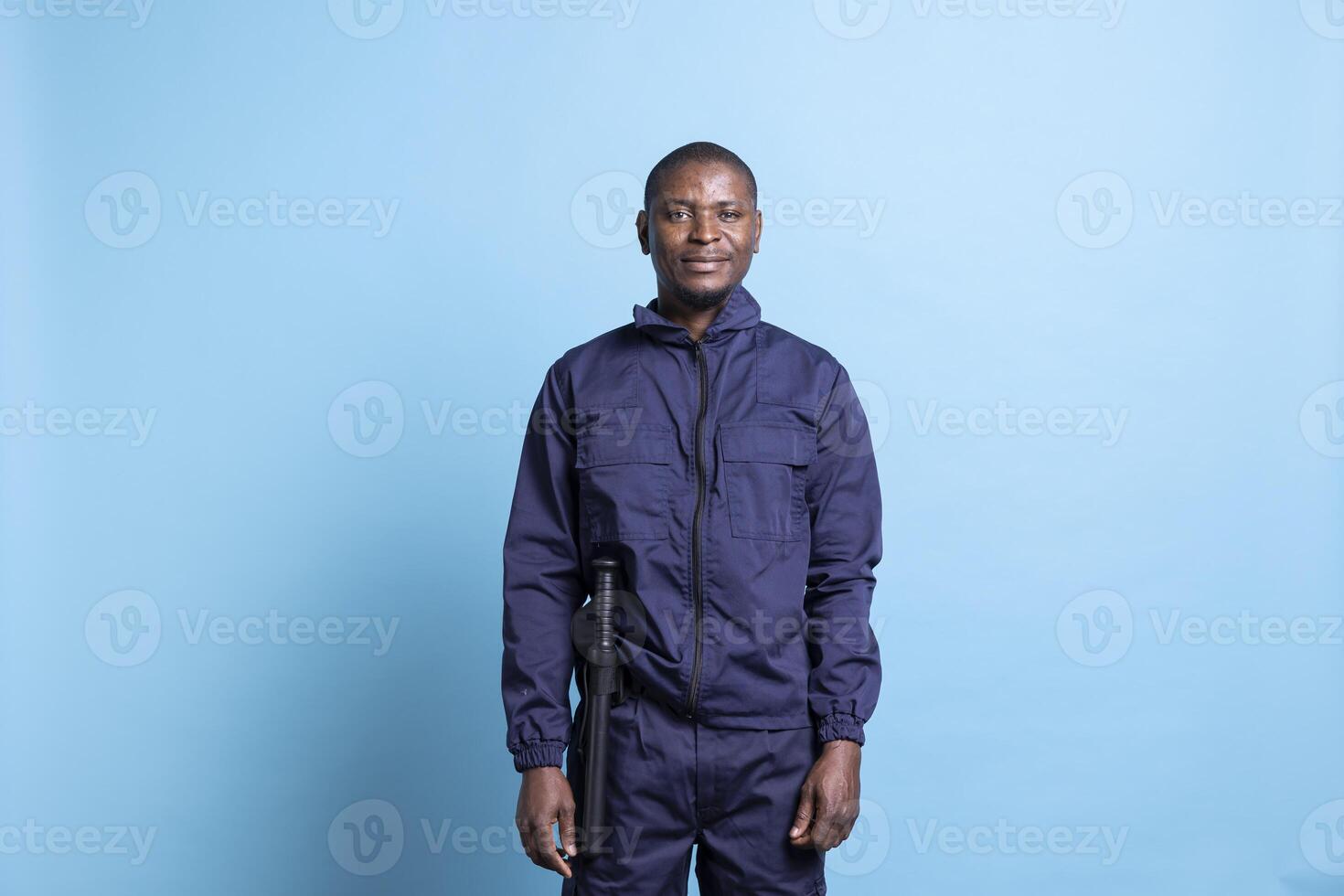 African american security agent safeguarding the perimeter in front of the camera, dressed in uniform with baton. Male defense personnel working on property protection, patrol service. photo