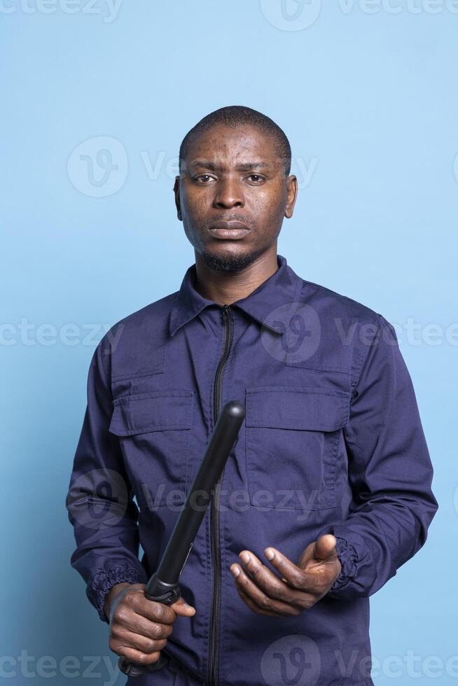 Armed security officer holding his baton and getting ready for a fight, trained to engage in combat for protection if necessary. Skilled man bodyguard in uniform preparing for any emergency. photo