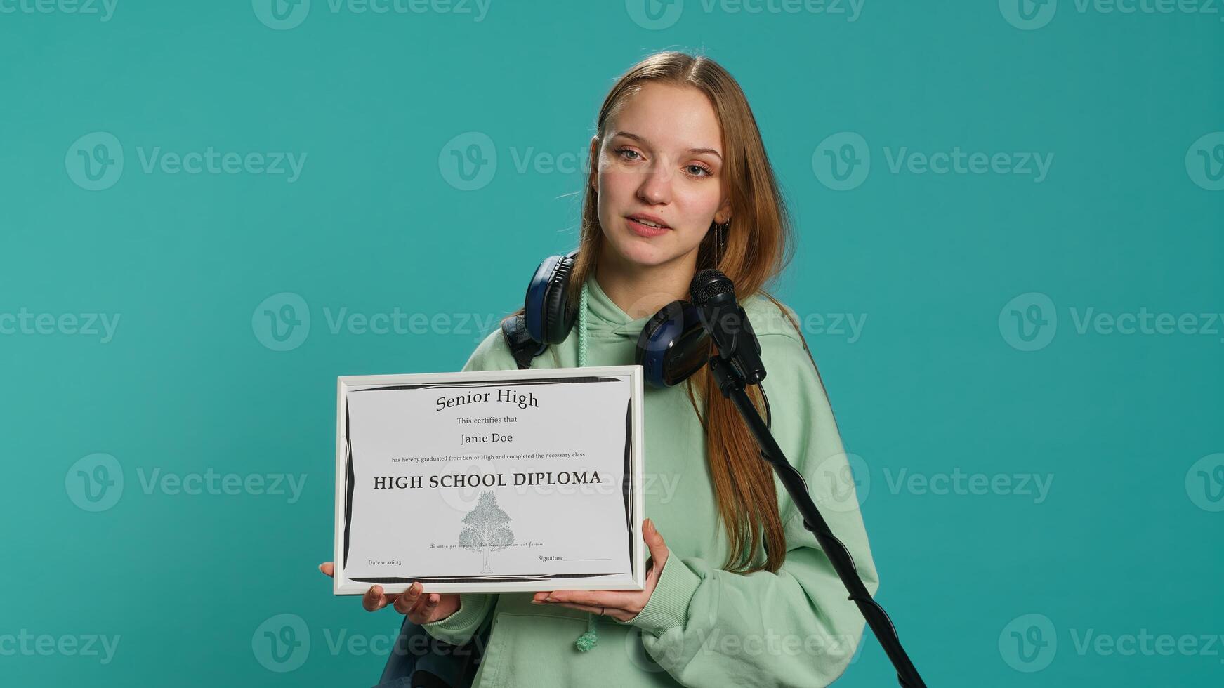Overjoyed student celebrating achievement, holding diploma, using microphone to do speech, studio background. Woman using mic to share wisdom with colleagues after finishing school, camera A photo