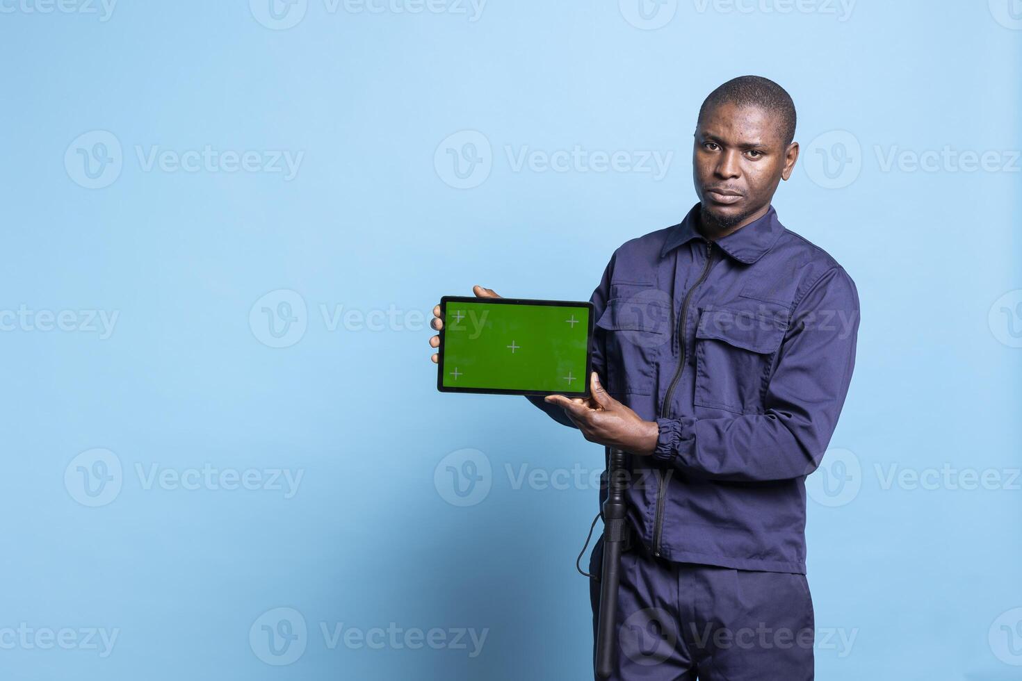 Security officer using a tablet to show an isolated copyspace screen on camera, wearing his work uniform and smiling. Proud bodyguard presenting mockup display on device in studio. photo