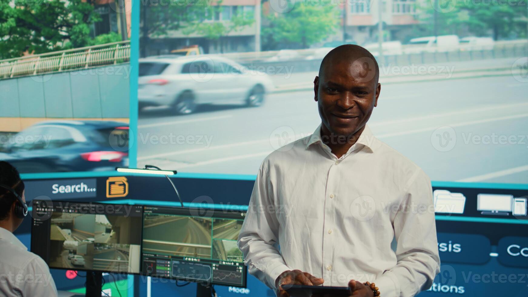 Team leader supervising his team in control center office to work on monitoring traffic by following real time surveillance . Diverse agency employees examining city streets via CCTV. Camera B. photo
