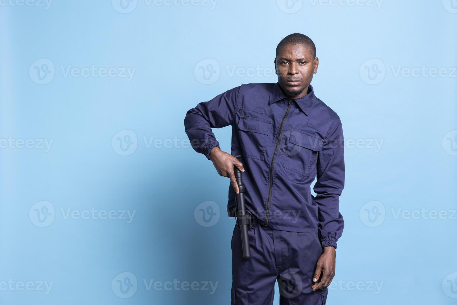 African american security agent taking baton in his hand on camera, preparing for a fight to protect and safeguard something. Professional patrolling staff armed with a bat, emergency defense. photo