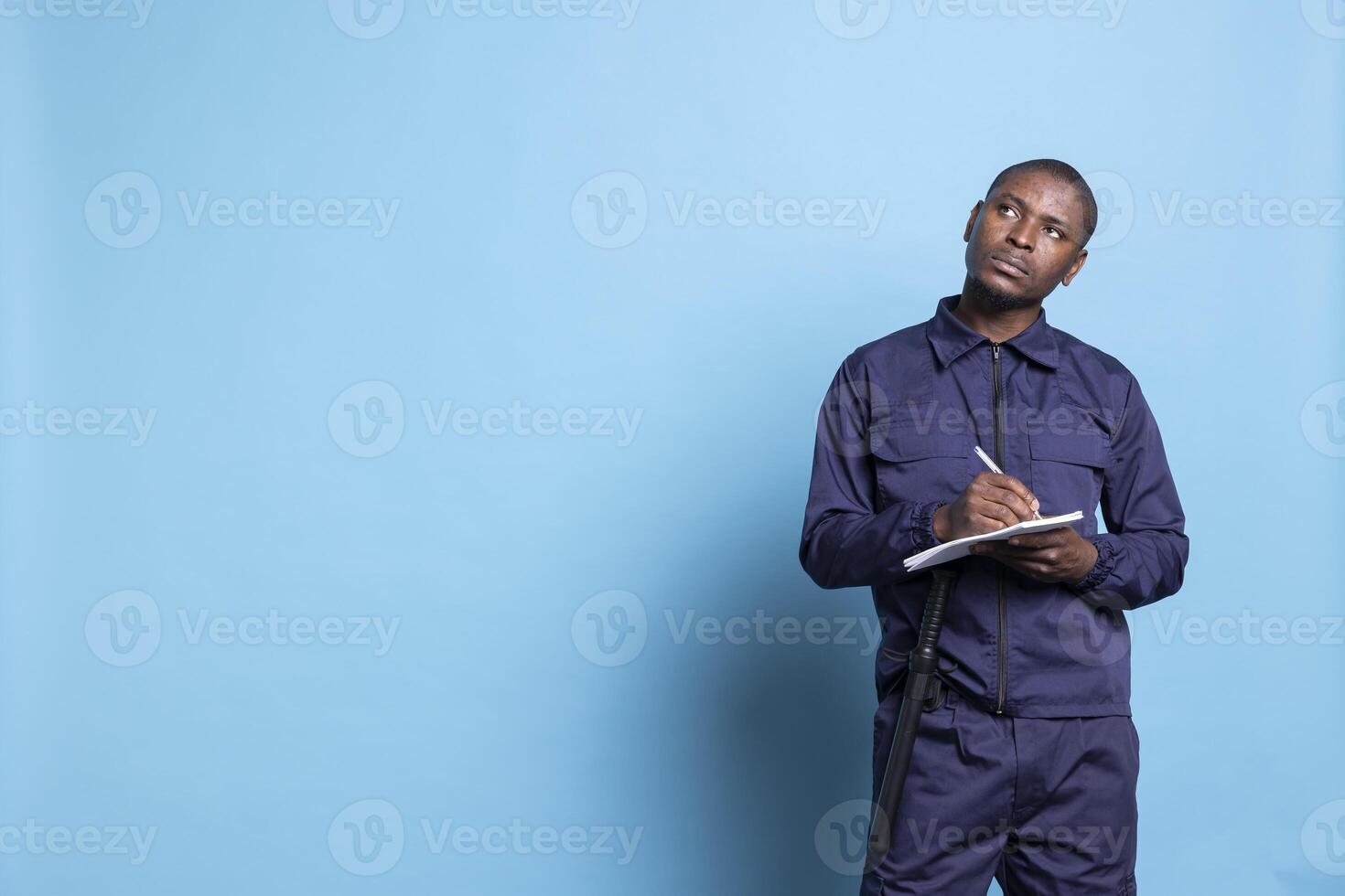 African american security agent writing details on his notebook files, keeps track of information while he is on safeguarding duty. Mall guard taking notes to ensure protection, activities checklist. photo