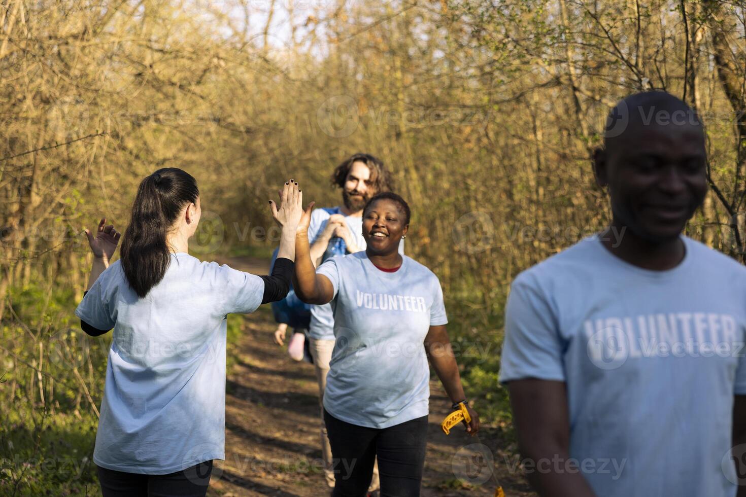 Joyful group of environmentalists doing high five with each other, saying congratulations and being satisfied with their teamwork efforts. Leader praising her colleagues, resilience. photo