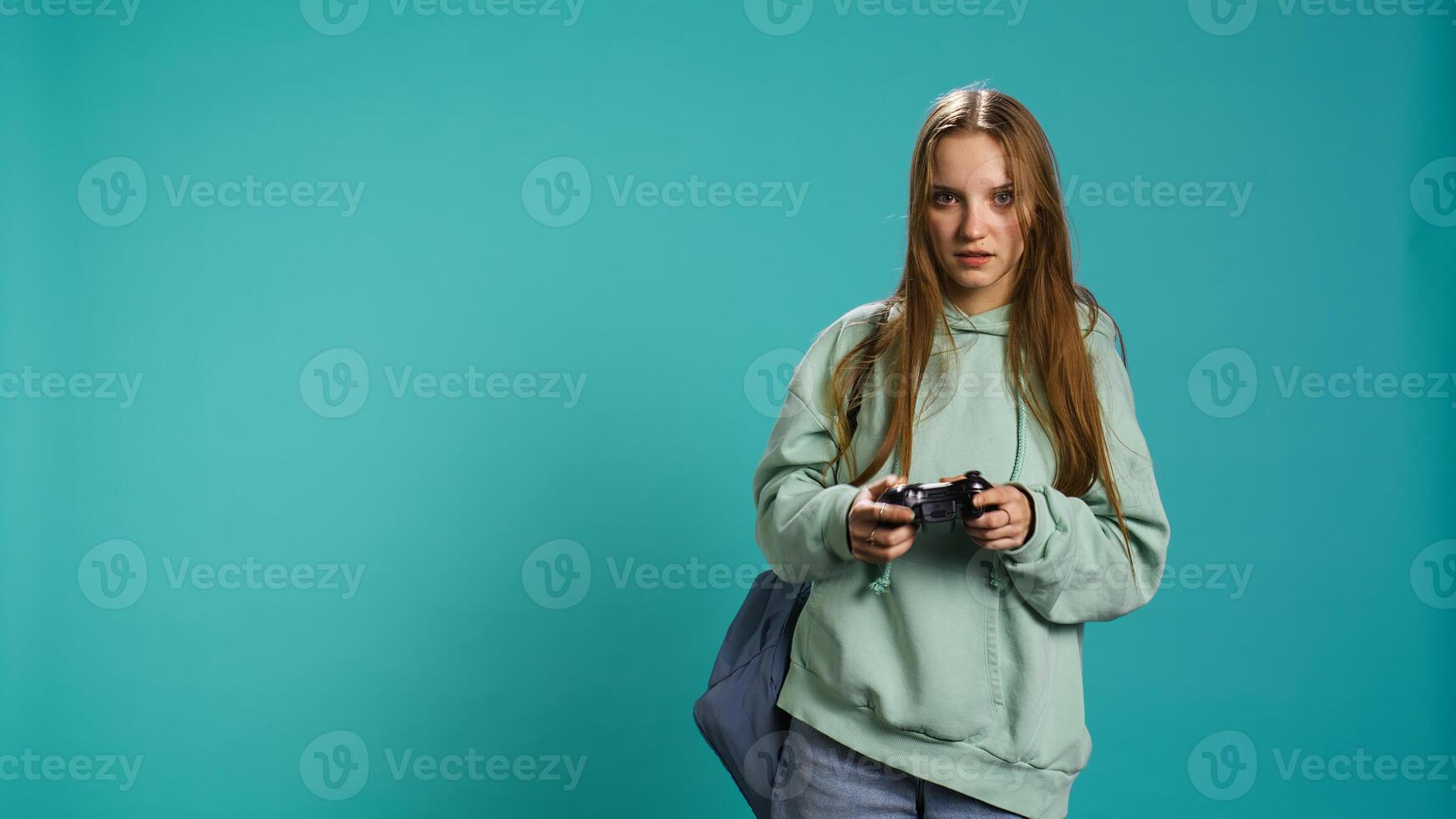 Young girl spamming controller buttons, disappointed after receiving game over screen. Woman upset after losing videogame, playing with gamepad, studio background, camera B photo
