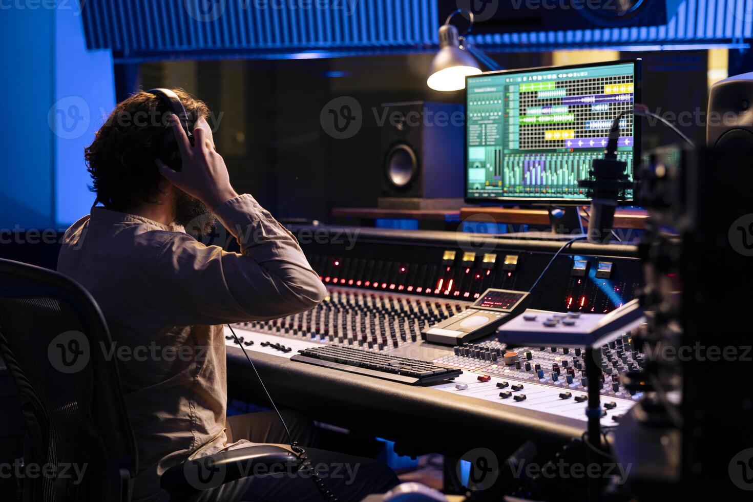 Sound engineer using headset to edit tracks on audio digital software, producer creates music and handling technical gear on control room dashboard. Technician does mix and master. photo
