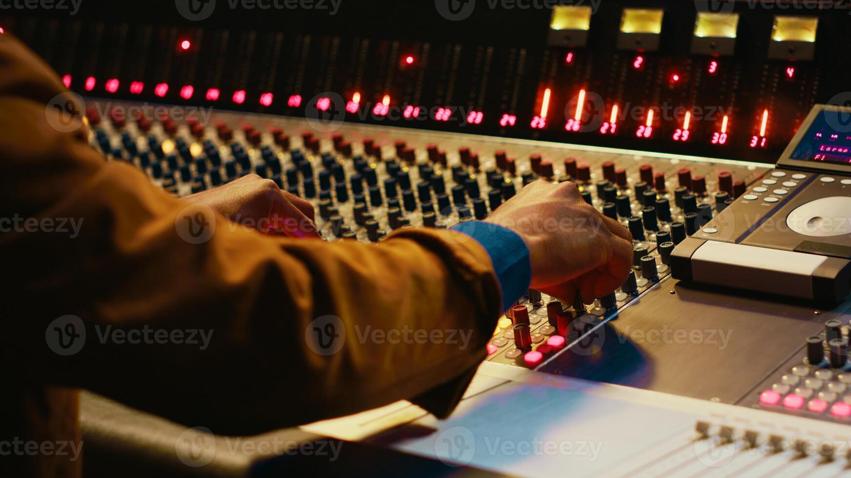 Audio technician producing new music at mixing console in control room, twisting knobs, pressing sliders and switchers. Producer working on processing and editing sounds quality. Camera A. photo