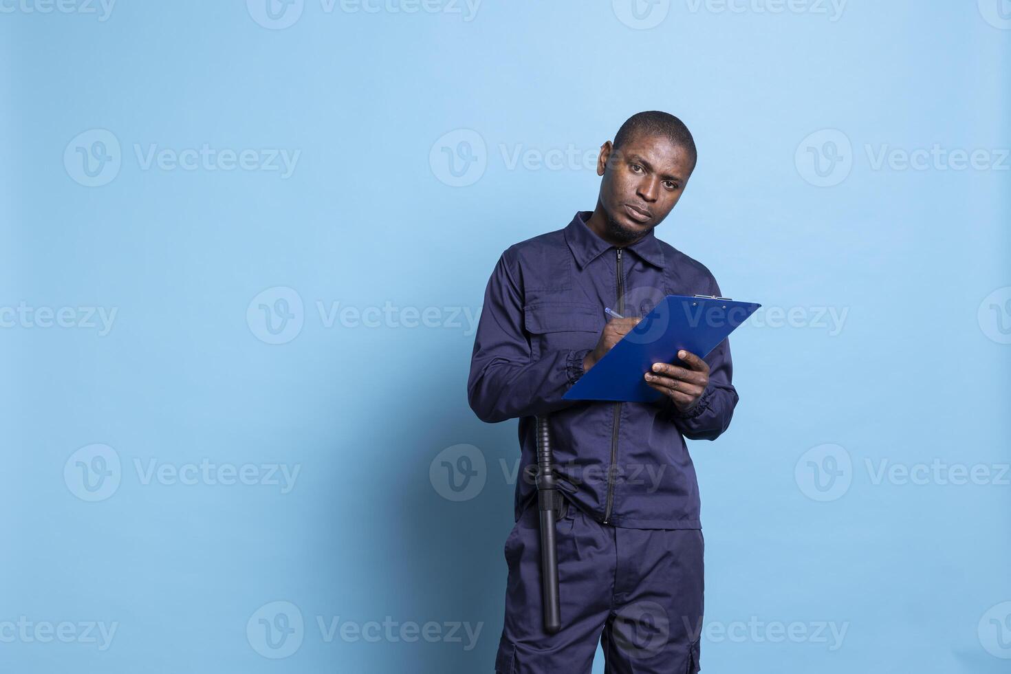 Mall bodyguard takes notes on his clipboard papers while on duty, safeguarding and protecting the perimeter. Skilled security agent writes details for an event, defense responsibility. photo