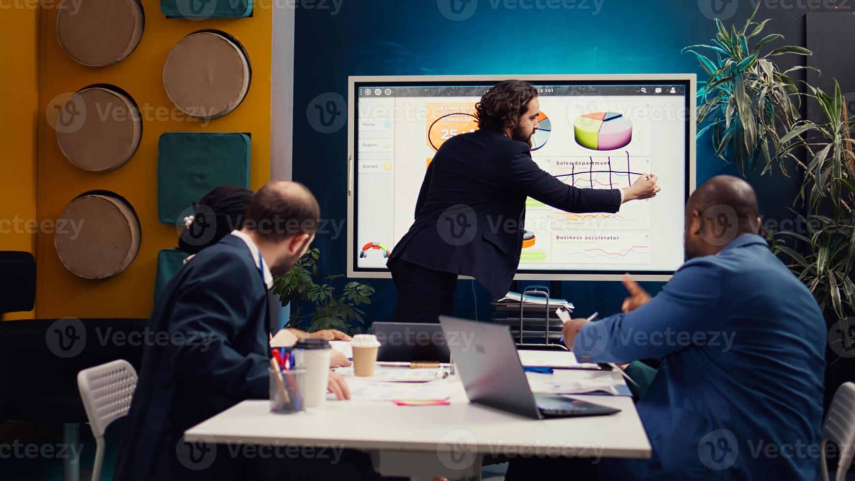 Financial analyst briefing his team about new company objectives, making budget and sales presentation with interactive board. Specialist addressing resource allocation and project planning. Camera B. photo