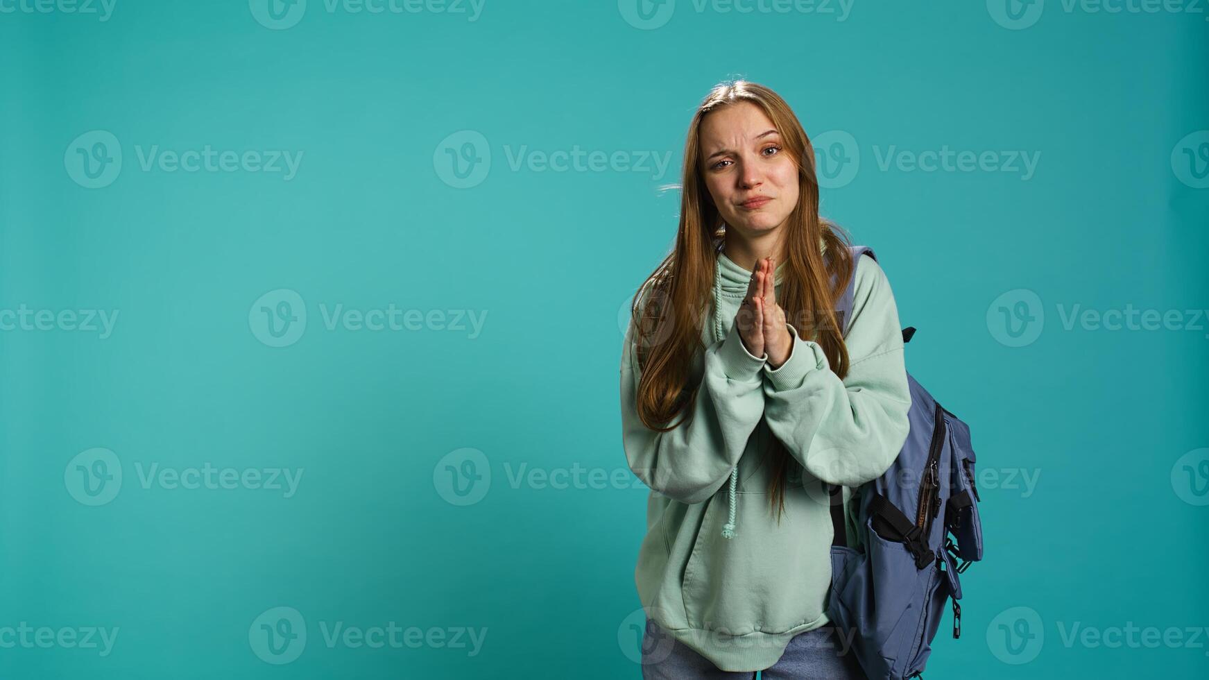 Woman doing begging hand gesture, in ardent need of favor from friend, isolated over studio background. Young girl doing please gesturing, requesting assistance, camera B photo