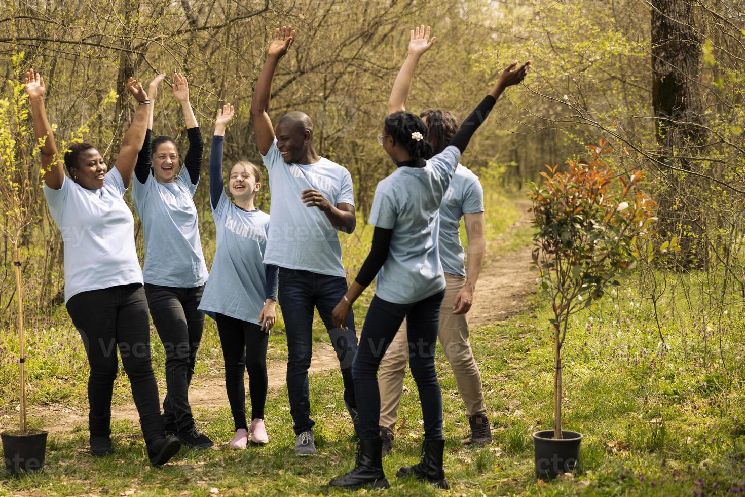 Diverse group of volunteers connecting hands after a successful ecology action, preserving nature and fighting for reforestation. People feeling happy with teamwork, joining forces to grow trees. photo