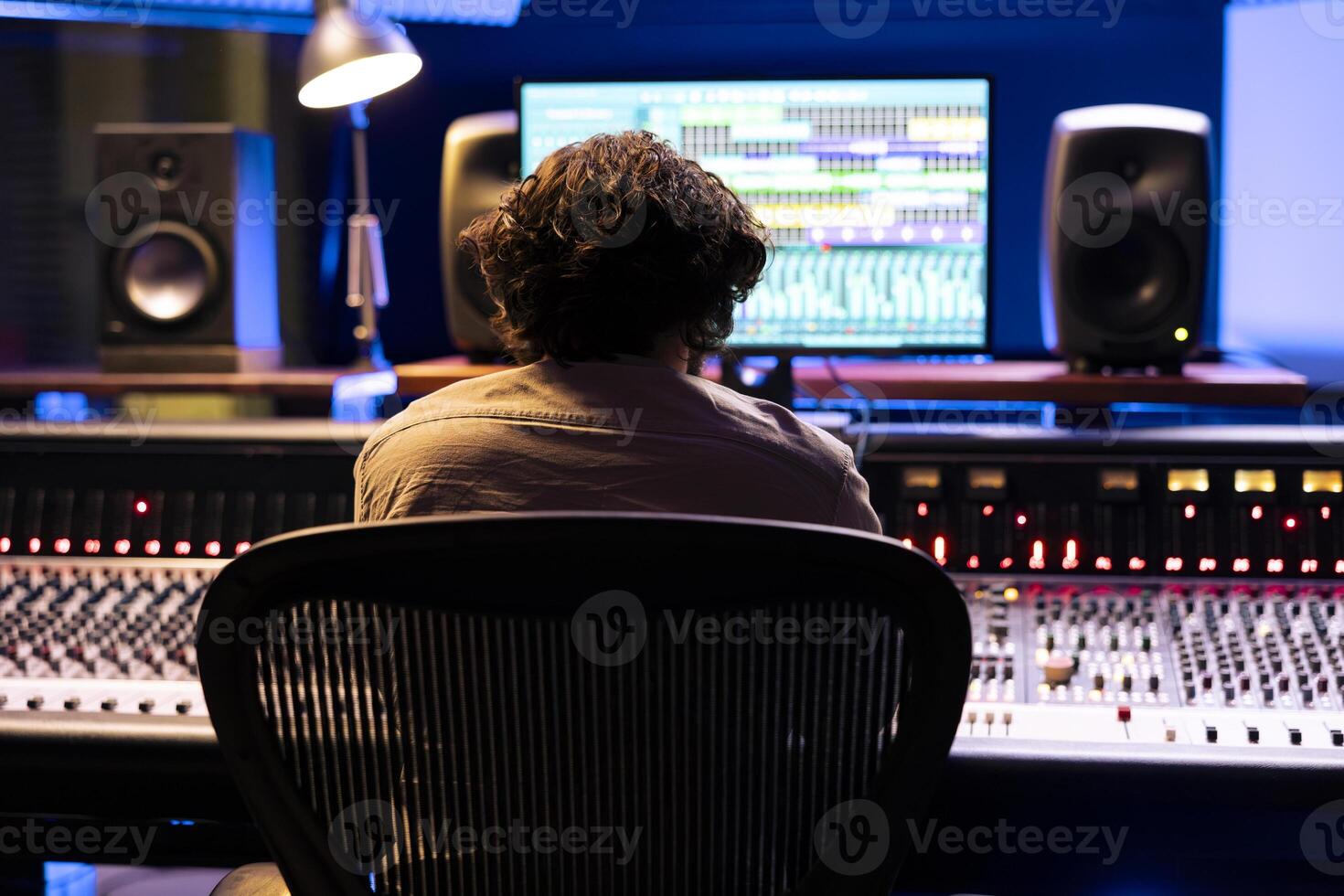 Audio technician editing tracks with digital software interface on pc, editing and processing music in control room at studio. Young expert producing music with stereo technical equipment. photo