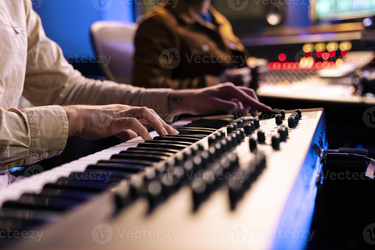 Young composer songwriter recording his piano notes in control room, playing electronic keyboard in professional studio. Talented musician performing live on midi controller synthesizer. Close up. photo
