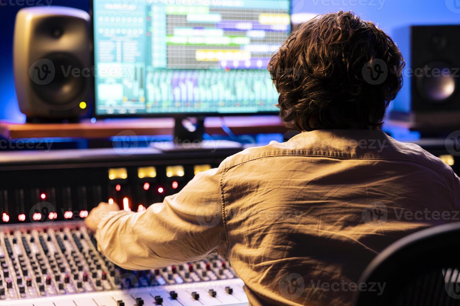 Audio engineer processing and composing tracks in control room, operating on digital software interface. Young sound technician mixing and mastering songs in professional studio, mixer station. photo