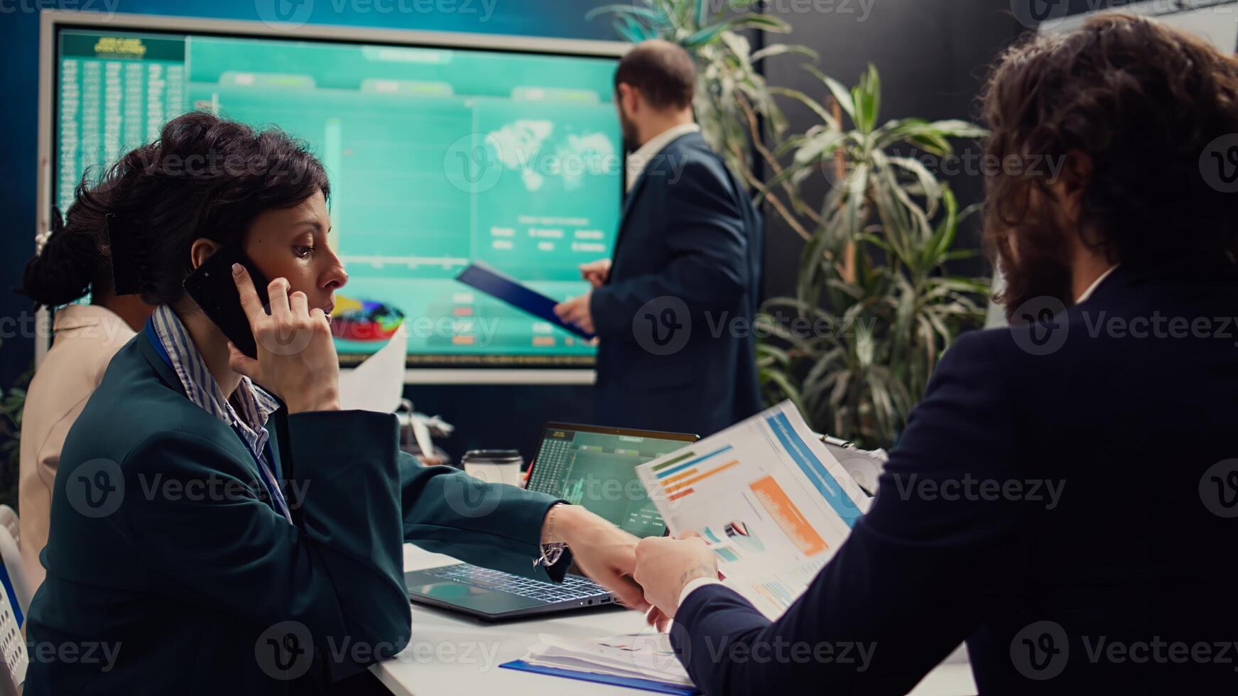 Business manager talking on phone call with the accountant to see the stock market trends progress, calling her associate to obtain more funding for a developing project. Boardroom. Camera B. photo