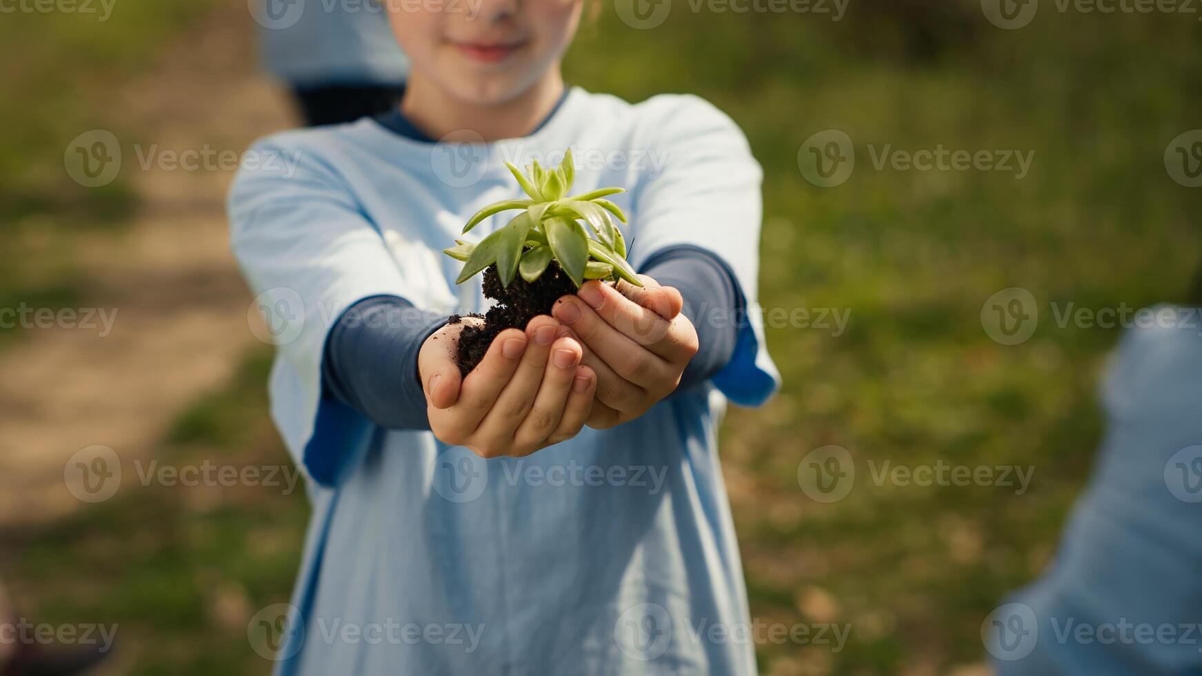 Small child holding soil with a green sprout in her hands, contributing to environmental preservation and natural cultivation. Young activist doing voluntary work to save the planet. Camera A. photo