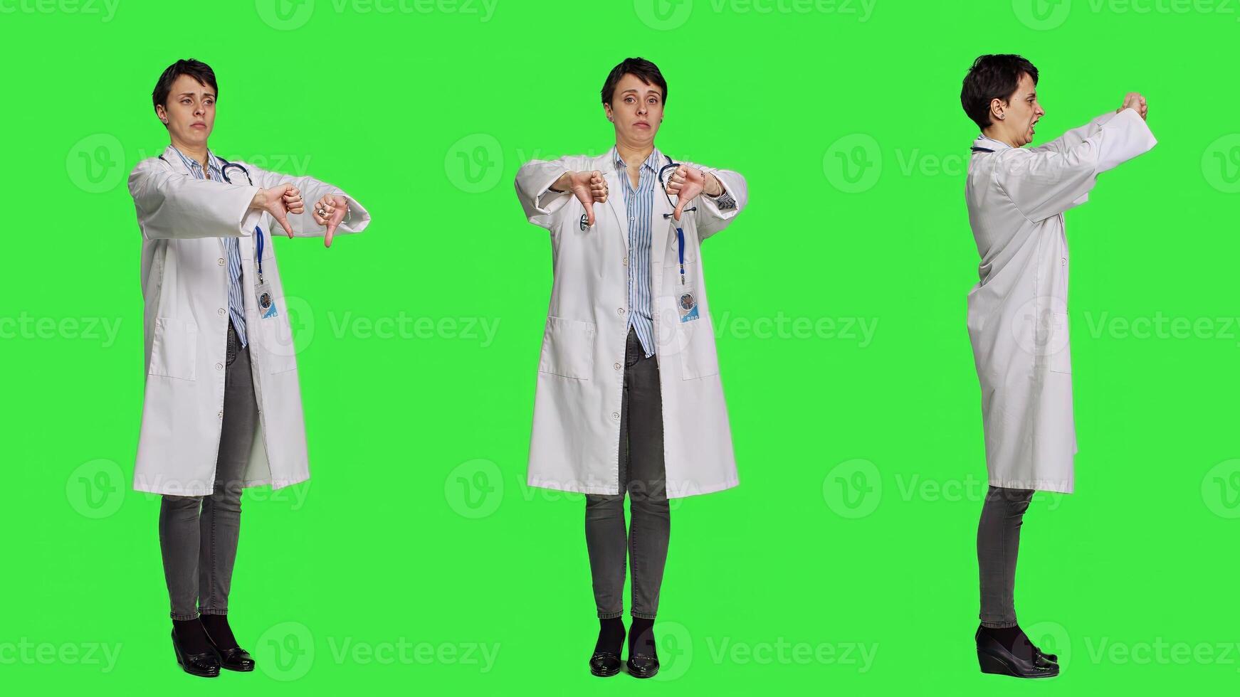 Displeased physician showing thumbs down symbol against greenscreen backdrop, expresses negativity and rejection. Doctor feeling dissatisfied and disagreeing with an idea, dislike sign. Camera A. photo
