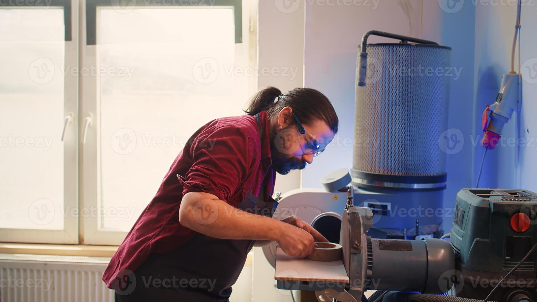 Manufacturer shaping wooden bowl on disc sander in assembling shop. Woodworking expert working in joinery, guiding wood against professional grinding machine rotating disc, camera B photo
