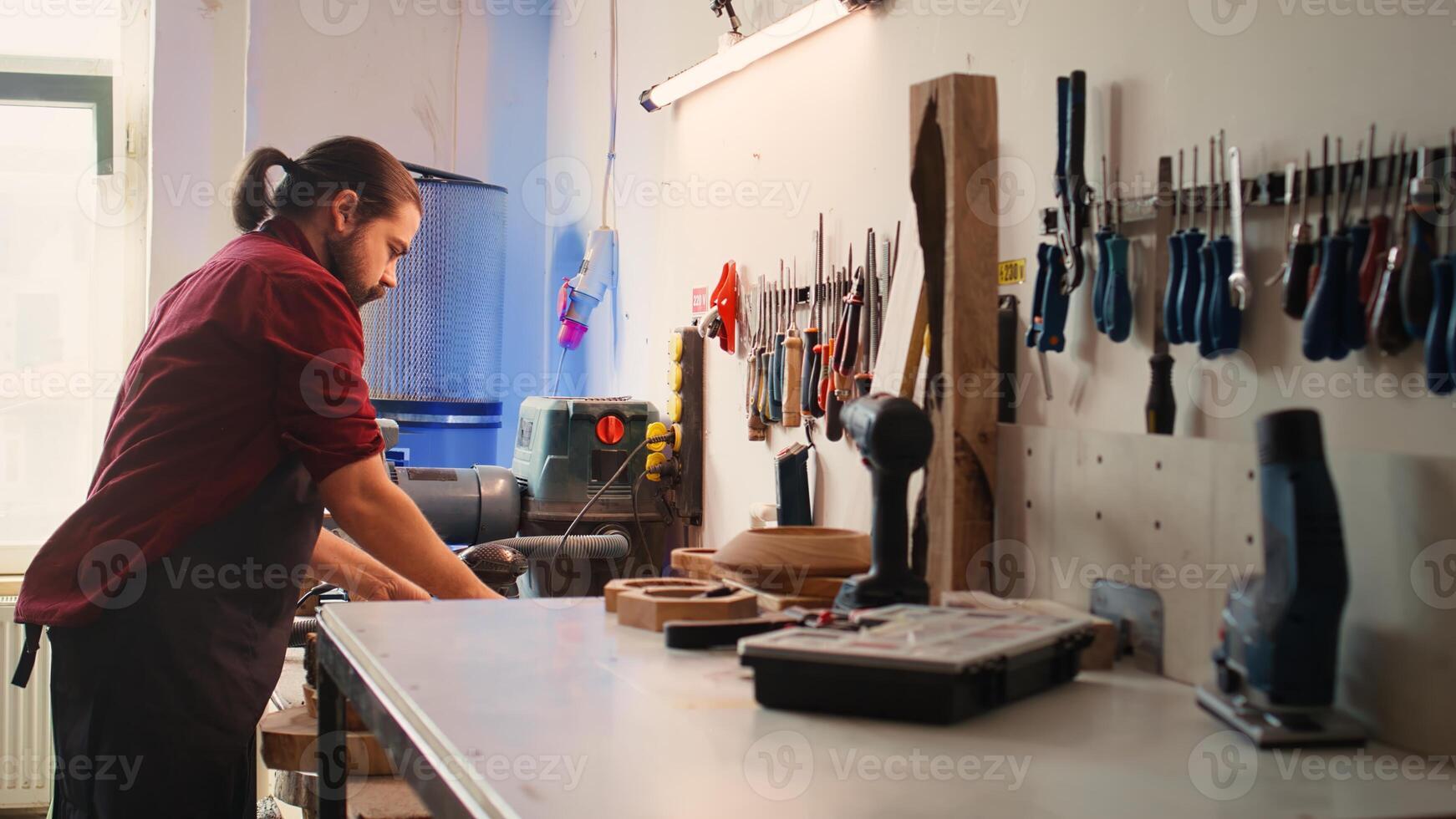 Carpenter selecting tool from rack to use on wood materials, helped by african american coworker. Craftsperson doing quality assurance on lumber pieces pile with BIPOC apprentice, camera B photo