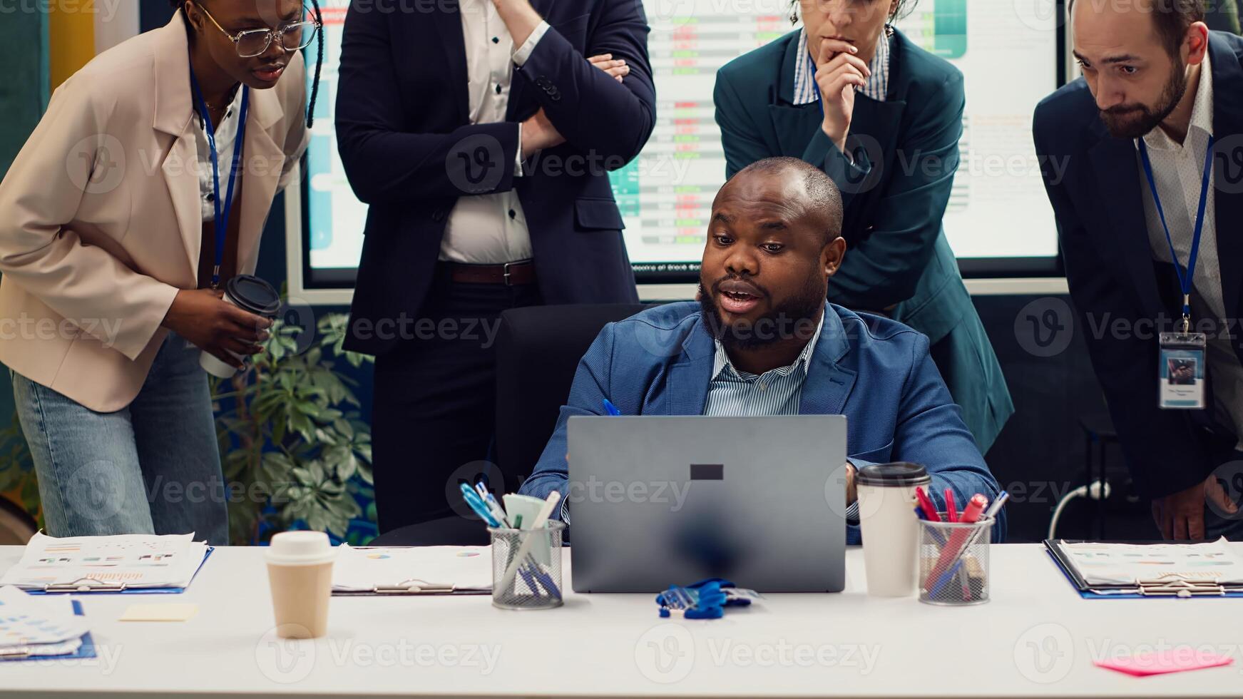 Diverse corporate employees analyzing project updates to ensure goal accomplishment, reviewing infographics on laptop and finding ways to obtain new funds. Business management team. Camera A. photo