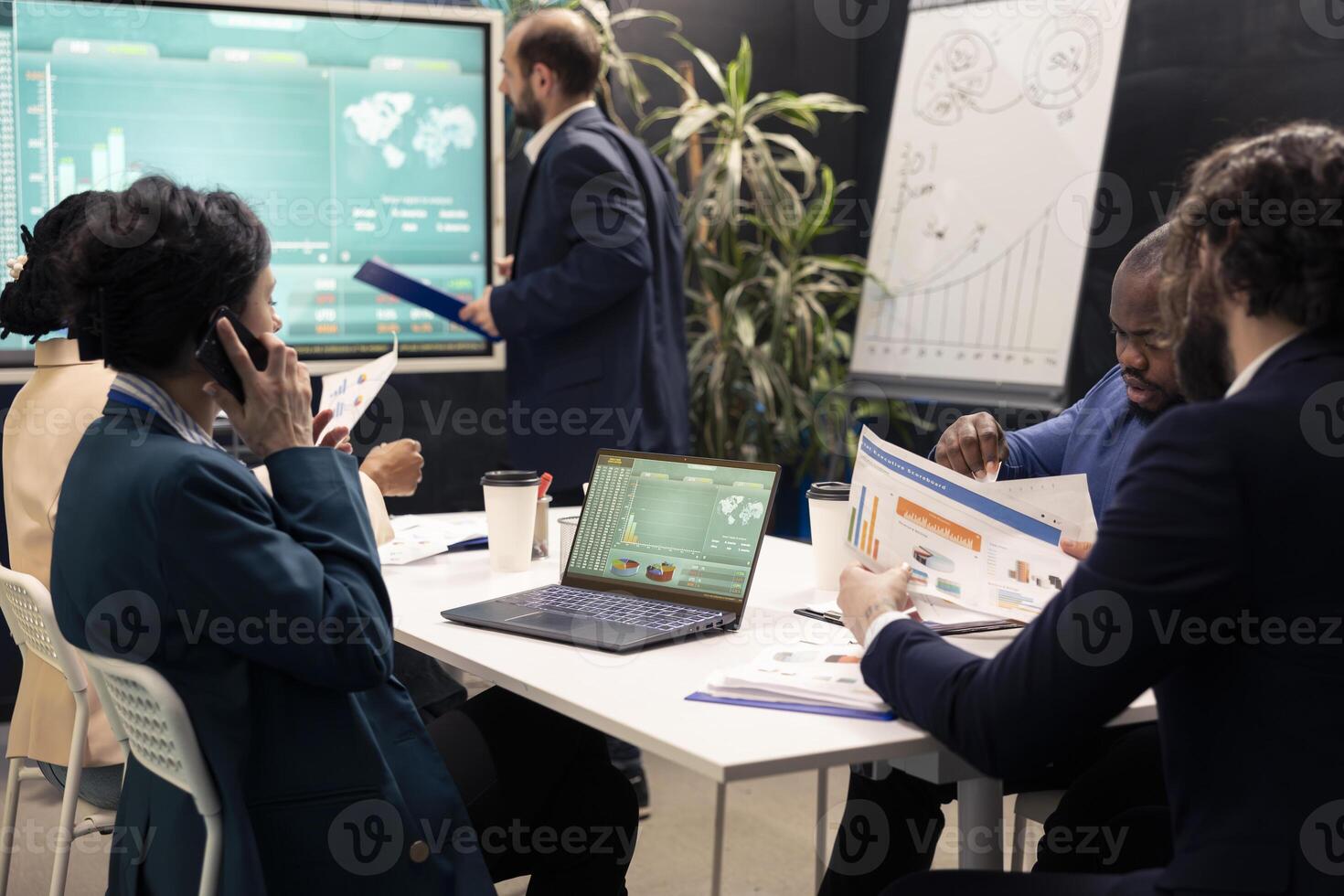 Team leader talking on phone call with the accountant to check stock trends progress, calling her business partner to obtain more funds for a developing project. Boardroom conference. photo