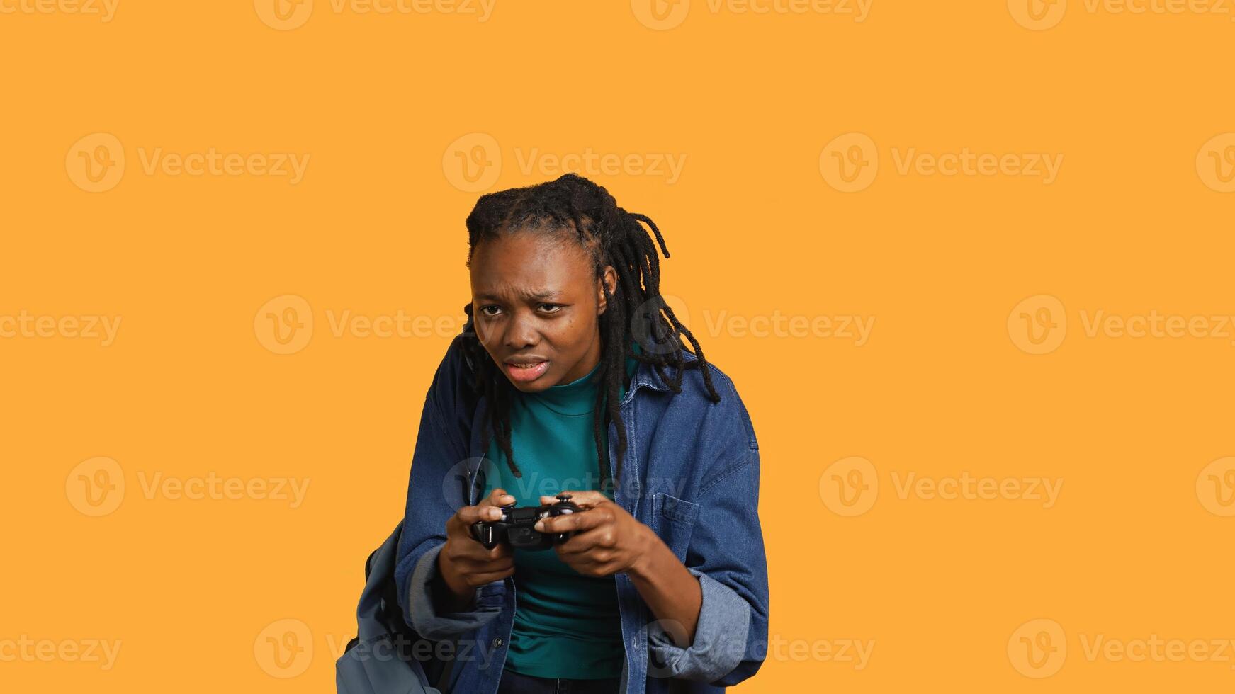 African american gamer holding controller, focused on finishing difficult videogame level. Woman gaming with gamepad, solving quests, isolated over studio backdrop, camera A photo