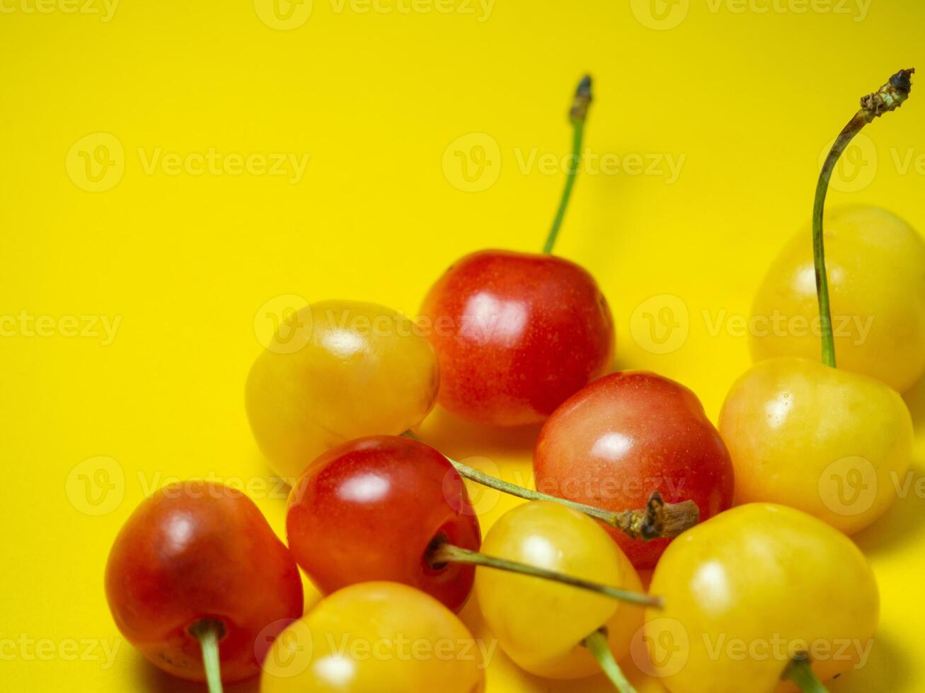 Sweet cherry with a stem on a yellow background. Bright table. Natural berries on the table. Delicious food. Berries of different colors. photo