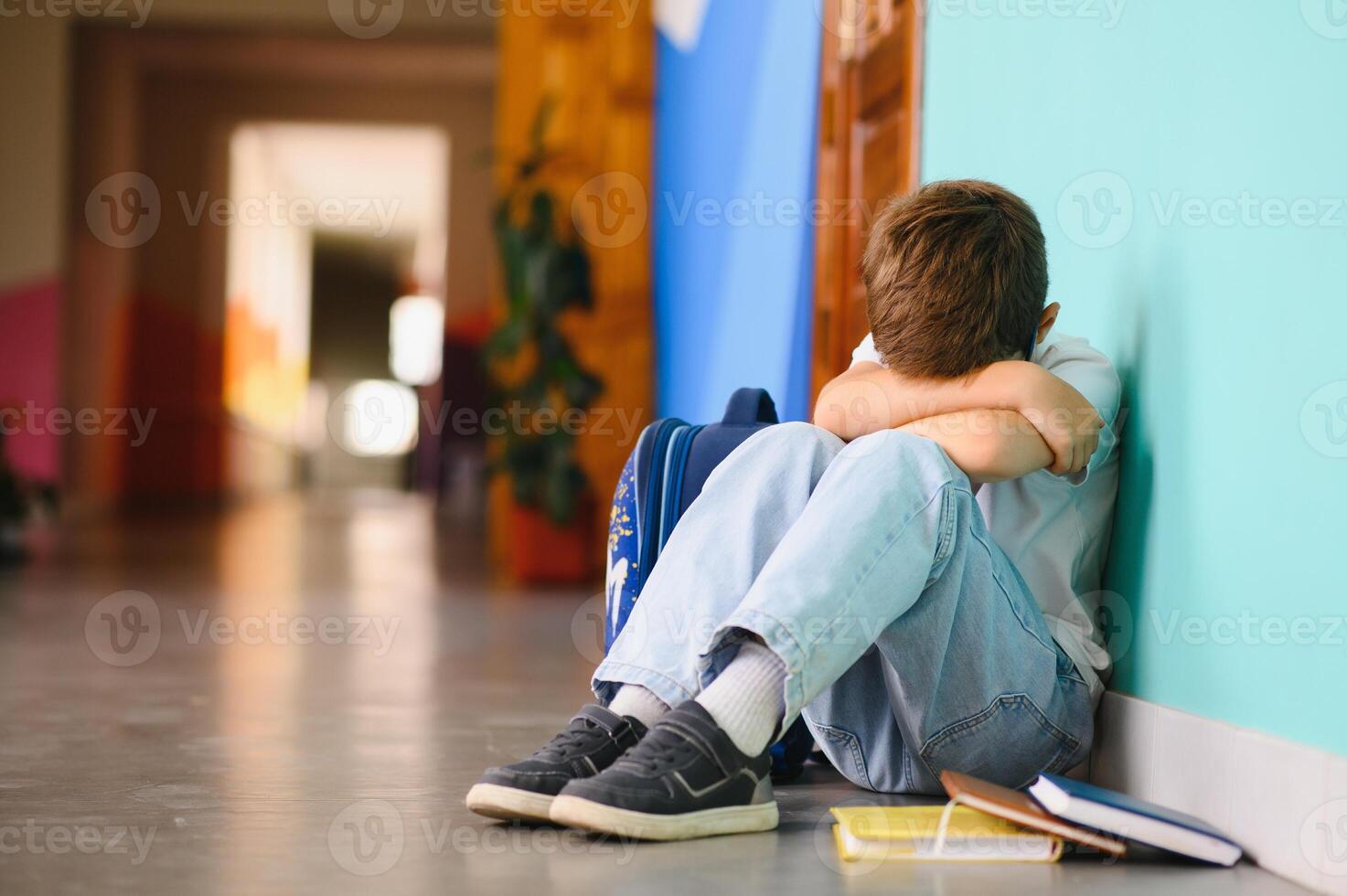 Young boy sitting alone with sad feeling at school. Bullying, discrimination and racism concept with copy space photo