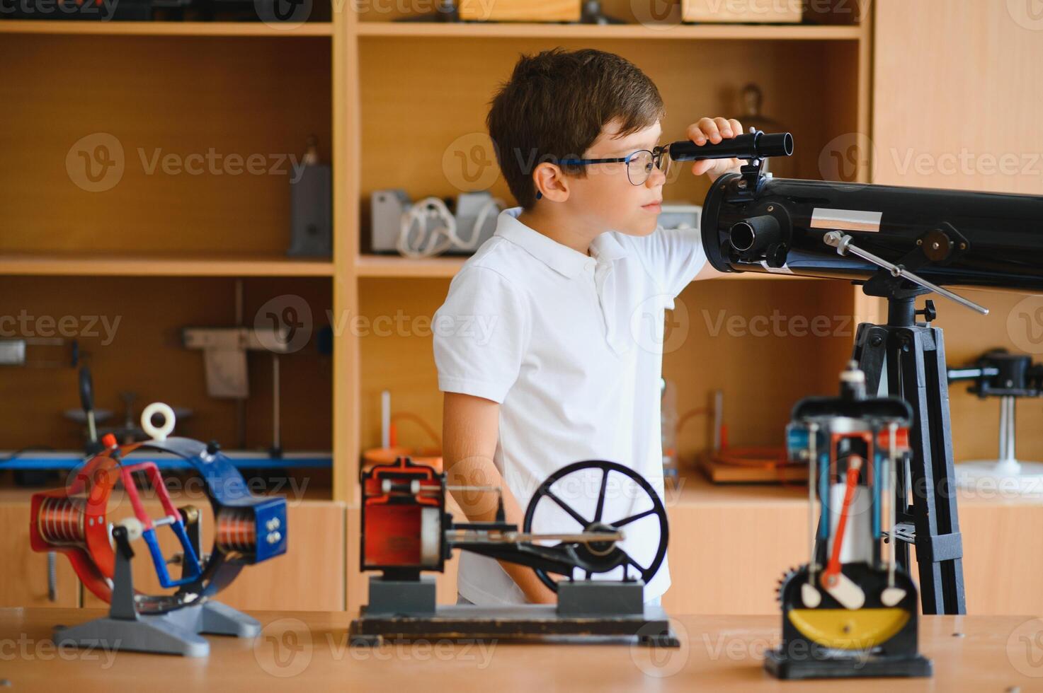 Physics lesson. A student at a desk with scientific instruments and a telescope photo