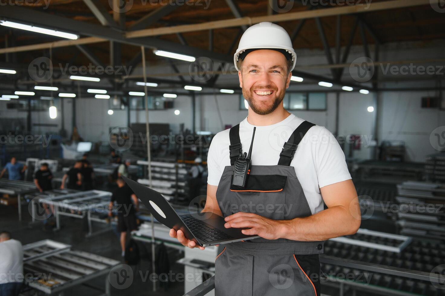 Men industrial engineer wearing a white helmet while standing in a heavy industrial factory behind photo