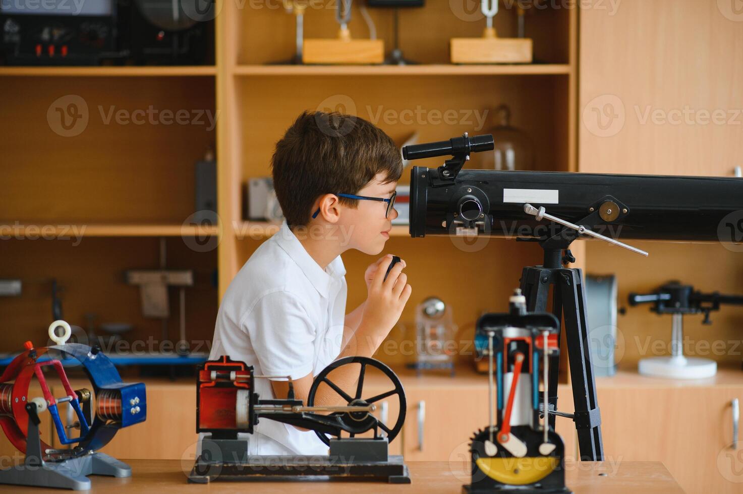 Physics lesson. A student at a desk with scientific instruments and a telescope photo