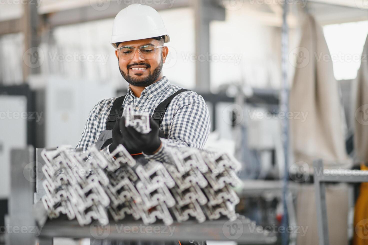 Young Indian male engineer wearing safety workwear standing in the factory photo