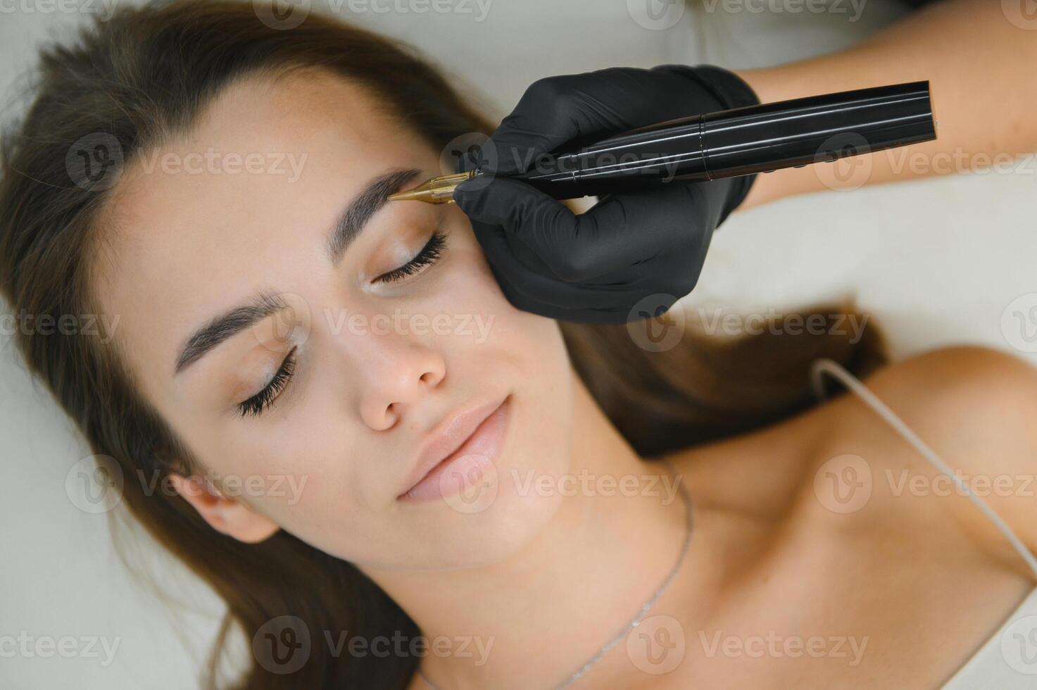 hands of the master who performs the procedure of permanent makeup of eyebrows. Permanent eyebrow makeup PMU for brunettes photo