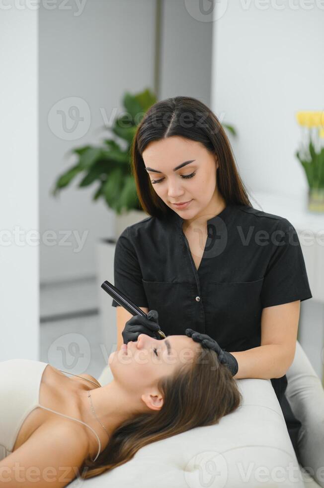 A cosmetologist applies permanent makeup to the eyebrows, eyebrow tattoo. eyebrow perm photo