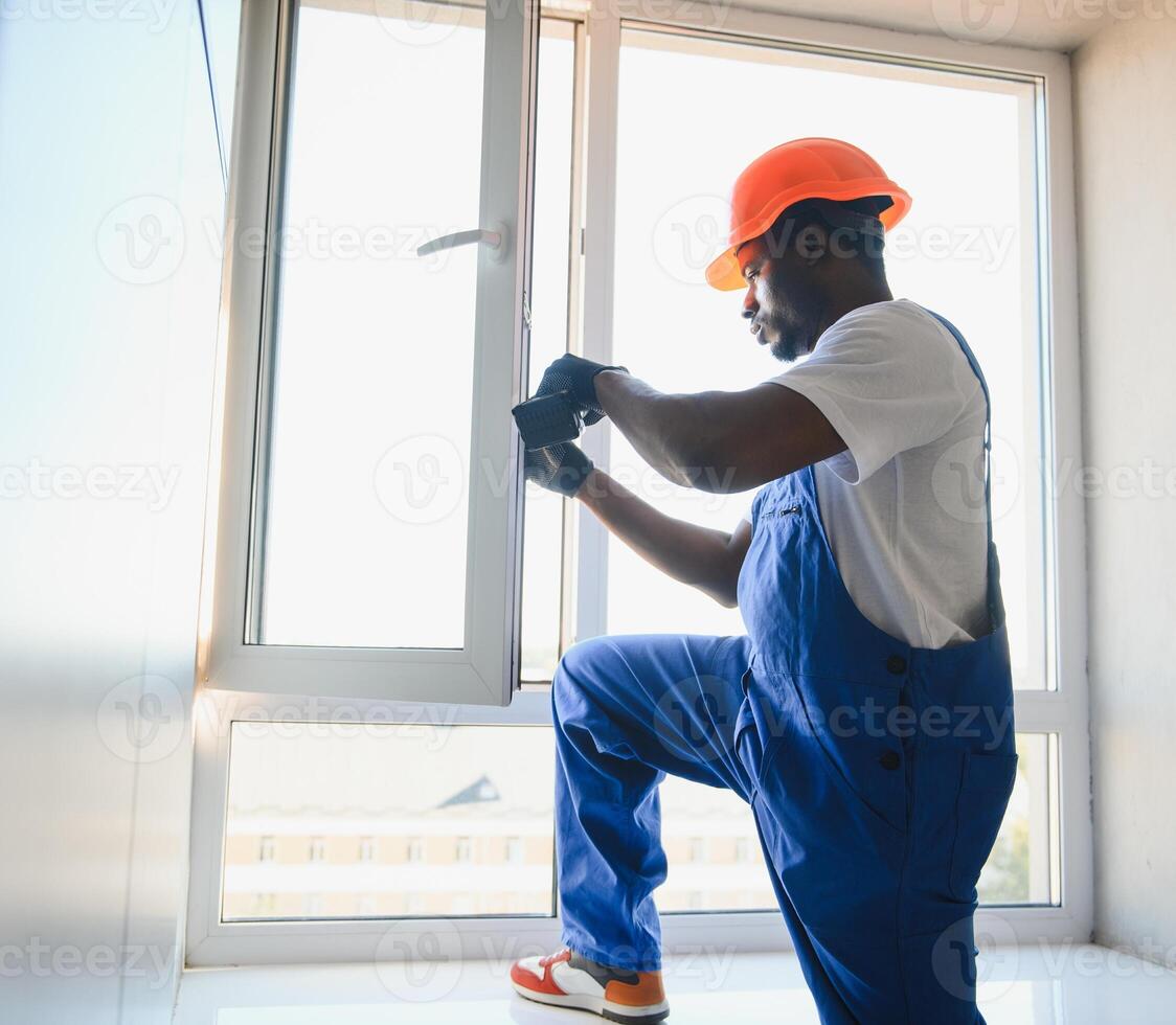 Worker in installing white plastic upvc window on house photo