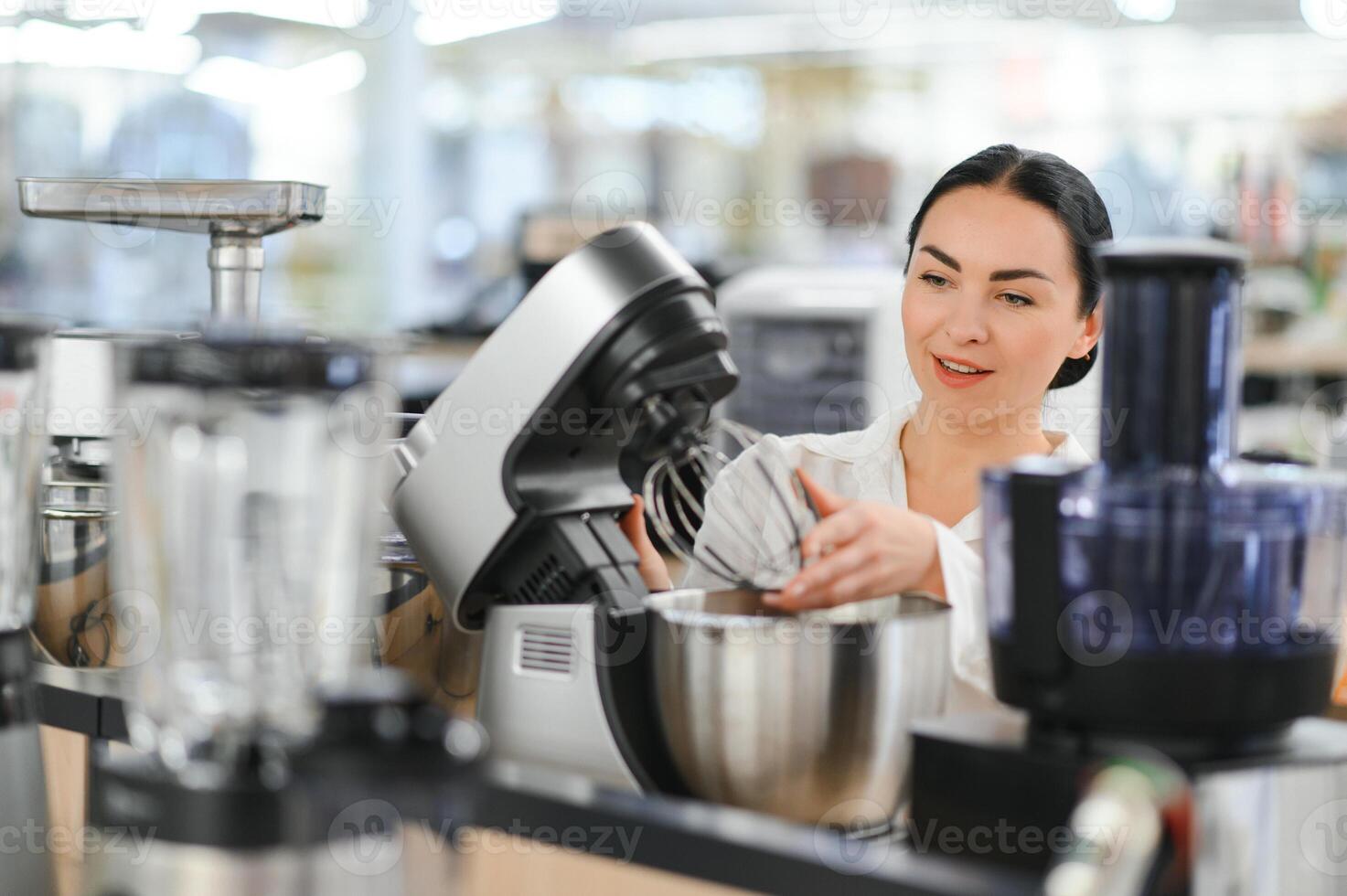 Young woman choosing kitchen mixer blender in home appliance shopping mall supermarket photo
