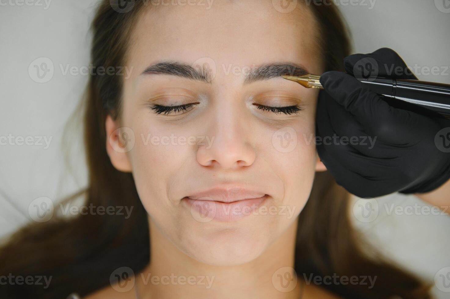 A cosmetologist applies permanent makeup to the eyebrows, eyebrow tattoo. eyebrow perm photo