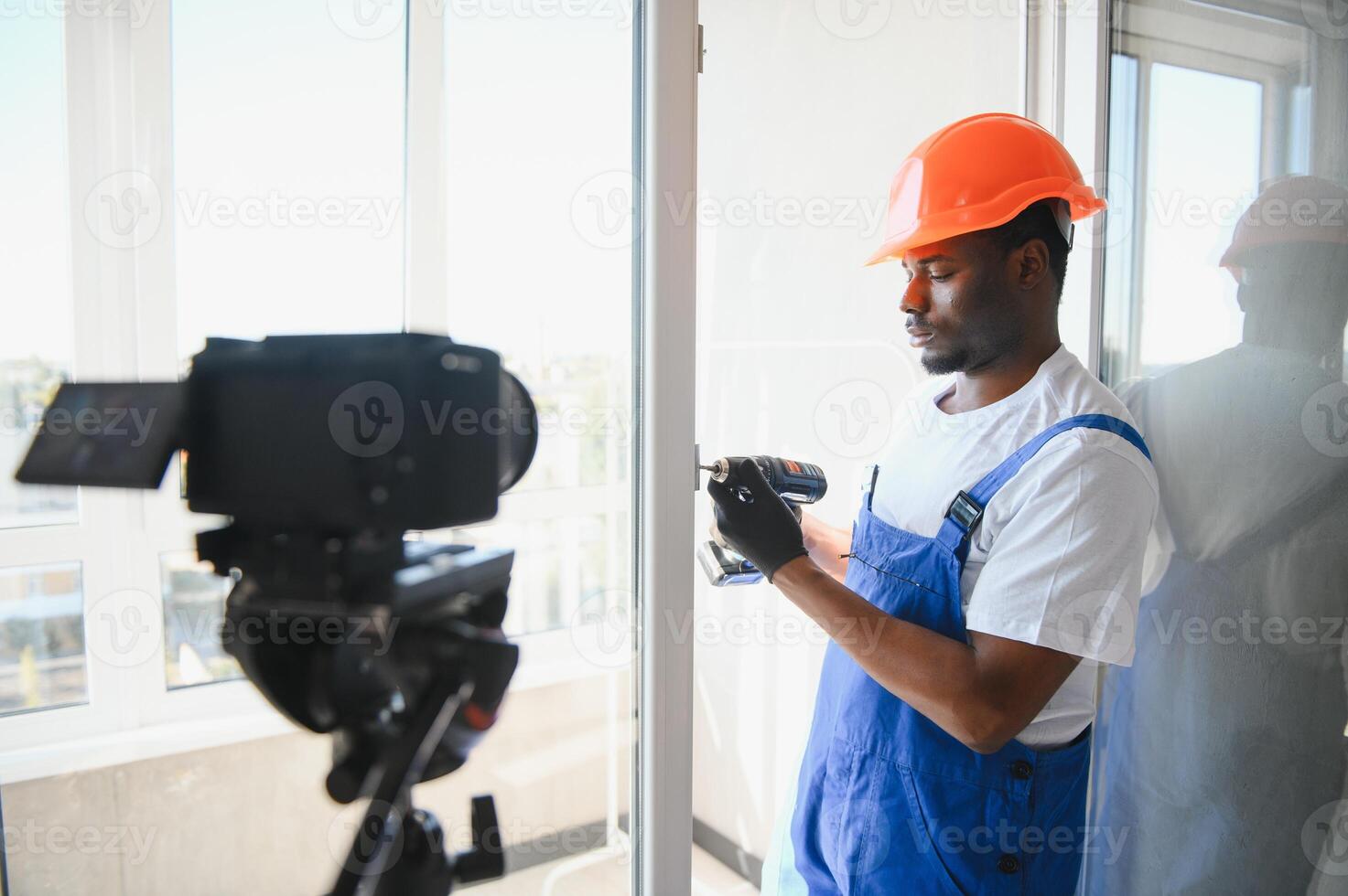 A worker inserts plastic windows and records a on a camera. Builder's blog photo